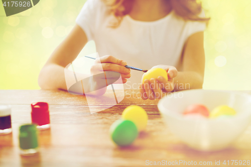 Image of close up of girl with brush coloring easter eggs