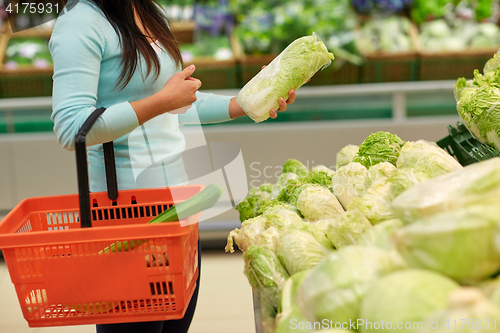 Image of woman with basket and chinese cabbage at grocery