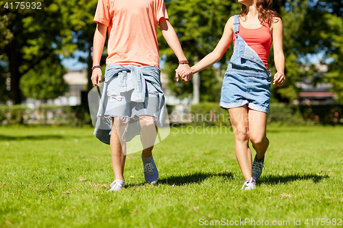 Image of happy teenage couple walking at summer park