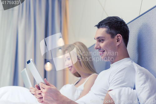 Image of smiling couple in bed with tablet pc computers