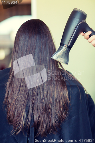 Image of stylist hand with fan dries woman hair at salon