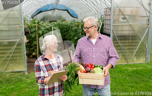 Image of senior couple with box of vegetables on farm