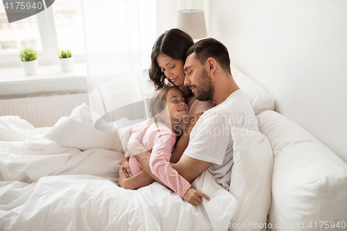 Image of happy family hugging in bed at home