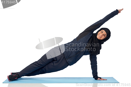 Image of muslim woman doing sport on mat