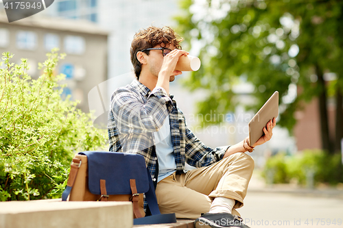 Image of man with tablet pc and coffee on city street bench