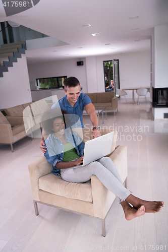 Image of multiethnic couple on an armchair with a laptop