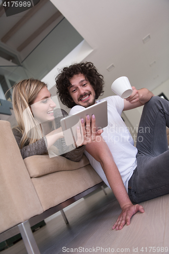 Image of couple relaxing at  home with tablet computers