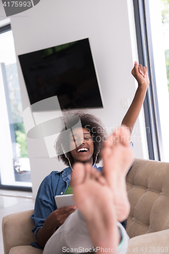 Image of African american woman at home in chair with tablet and head pho