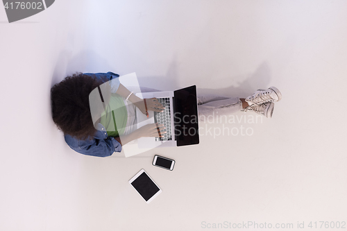 Image of african american woman sitting on floor with laptop top view