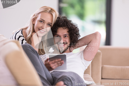 Image of couple relaxing at  home with tablet computers