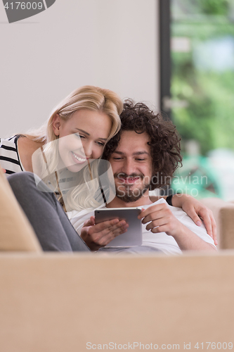 Image of couple relaxing at  home with tablet computers