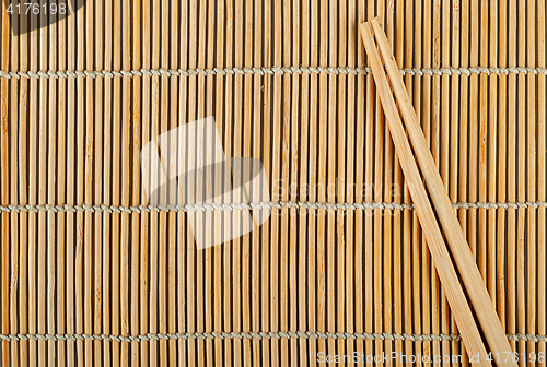 Image of Bamboo sushi mat and chopsticks on top