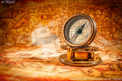 Image of Vintage compass lies on an ancient world map.