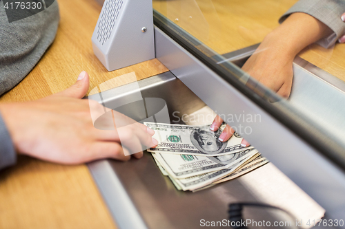 Image of clerk giving cash money to customer at bank office