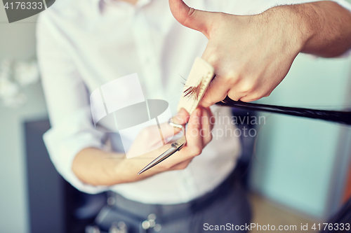 Image of male stylist hands cutting hair tips at salon