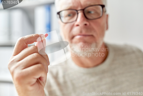 Image of close up of old man hand with pill