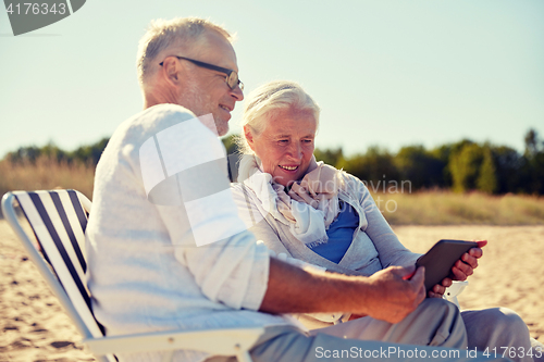 Image of happy senior couple with tablet pc on summer beach