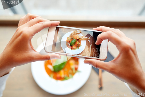 Image of hands with smartphone photographing food