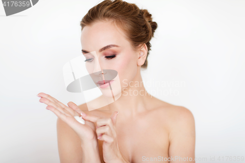 Image of happy young woman with moisturizing cream on hand