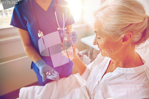 Image of nurse giving medicine to senior woman at hospital