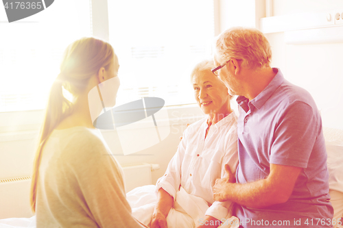 Image of happy family visiting senior woman at hospital