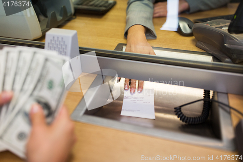 Image of bank clerk giving receipt to customer with money