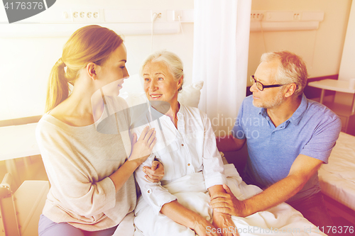 Image of happy family visiting senior woman at hospital