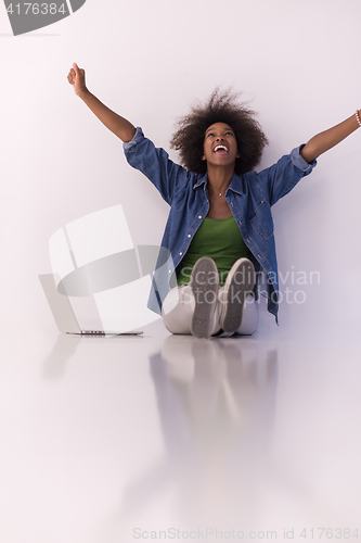 Image of african american woman sitting on floor with laptop