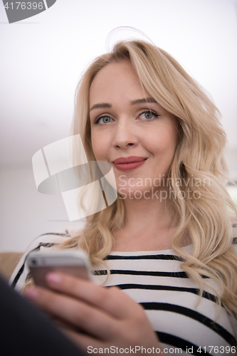 Image of woman sitting on sofa with mobile phone