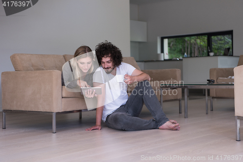 Image of couple relaxing at  home with tablet computers