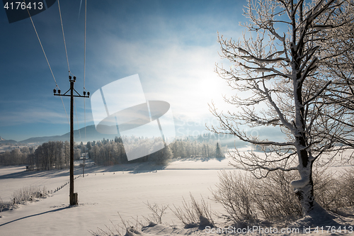 Image of Austrian Winter Wonderland with mountains, a power pole in fresh snow and haze