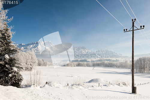 Image of Austrian Winter Wonderland with mountains, a power pole, fresh snow and haze