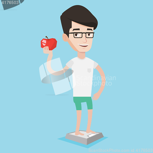 Image of Man standing on scale and holding apple in hand.