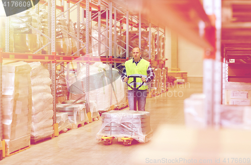 Image of man carrying loader with goods at warehouse