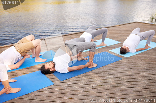 Image of group of people making yoga exercises outdoors