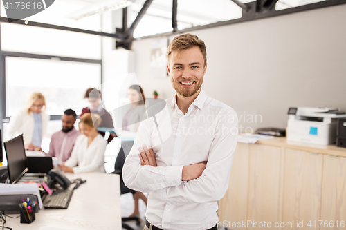 Image of happy young man over creative team in office