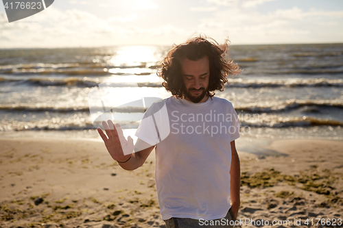 Image of happy man in white t-shirt on beach over sea