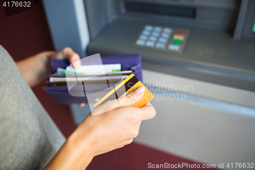 Image of hands with money and credit card at atm machine