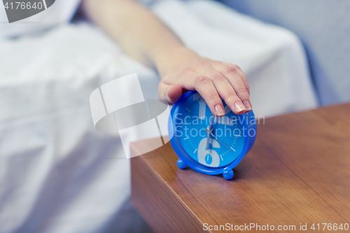 Image of close up of hand on alarm clock in bedroom