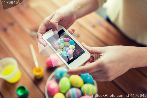 Image of close up of hands with easter eggs and smartphone