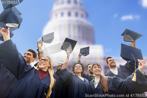 Image of happy students or bachelors waving mortar boards