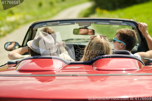 Image of happy friends driving in convertible car at summer