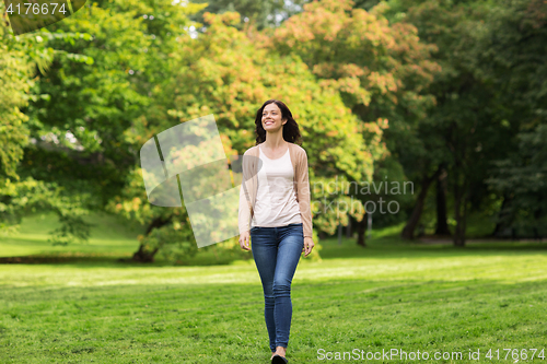 Image of beautiful happy young woman walking in summer park