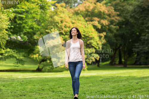 Image of beautiful happy young woman walking in summer park