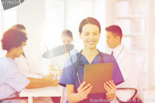 Image of happy doctor with tablet pc over team at clinic