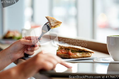 Image of woman with tablet pc and panini sandwich at cafe