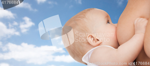 Image of close up of breastfeeding baby over blue sky