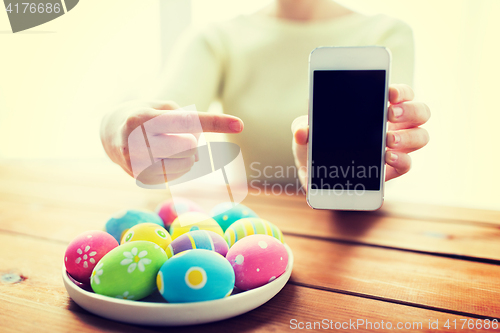 Image of close up of hands with easter eggs and smartphone