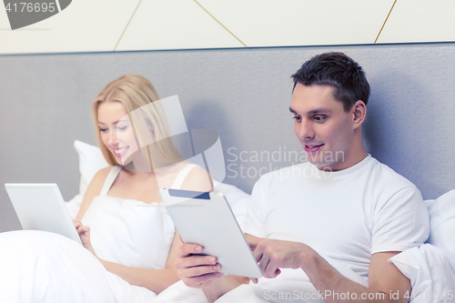 Image of smiling couple in bed with tablet pc computers