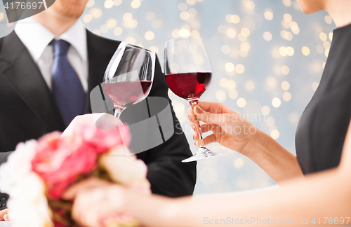 Image of close up of couple clinking red wine glasses